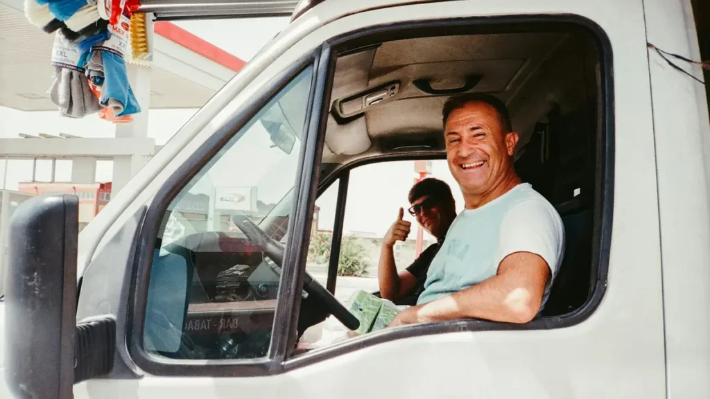 Livreur souriant au volant d'une camionnette blanche