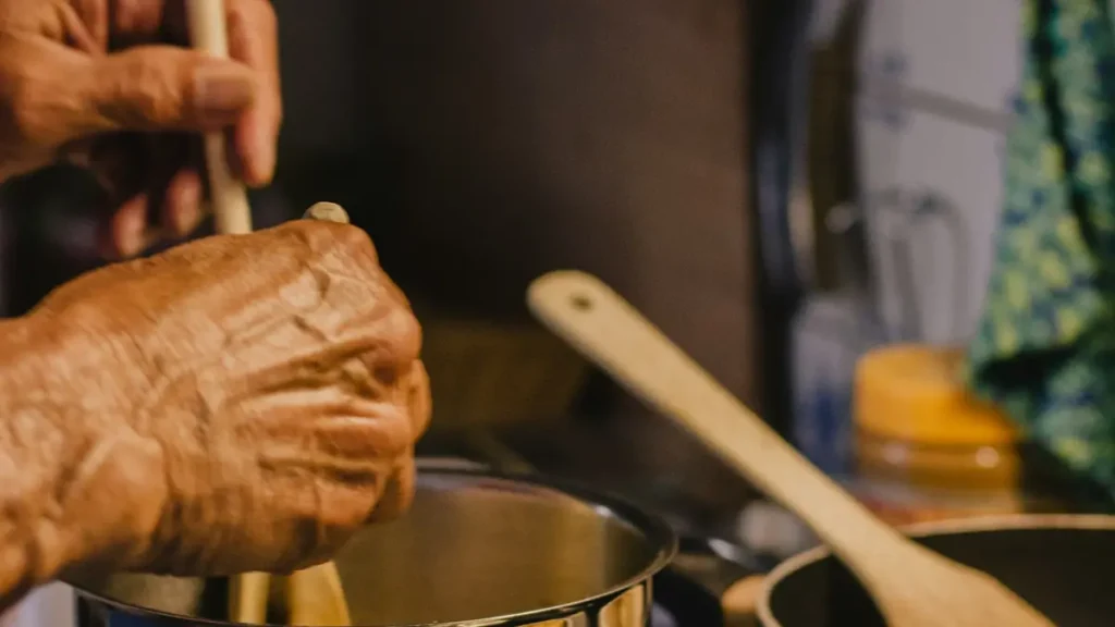 Mains d'un cuisinier qui remue une préparation dans une casserole