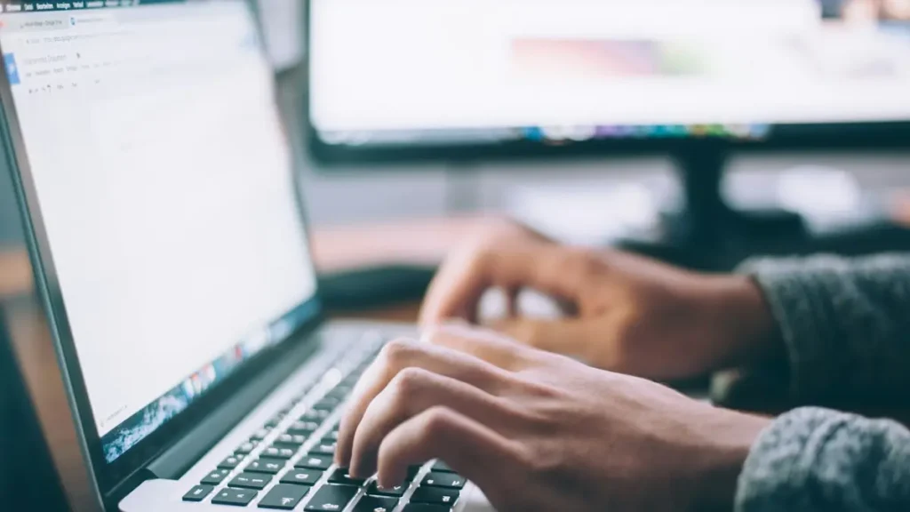 Mains qui tapent sur le clavier d'un ordinateur portable