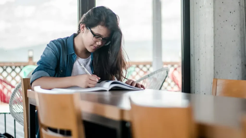 Étudiante qui travaille sur un livre à une table