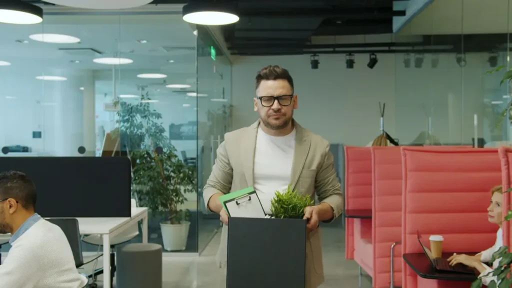 Homme qui quitte un bureau avec un carton d'affaires