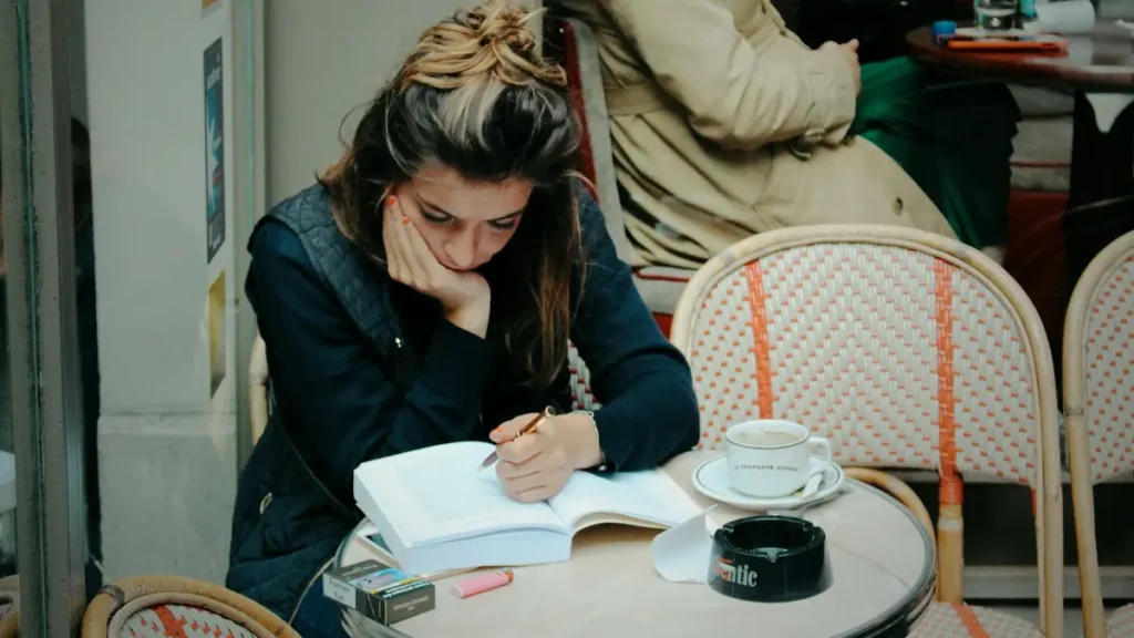 Étudiante qui écrit dans un carnet à la terrasse d'un café