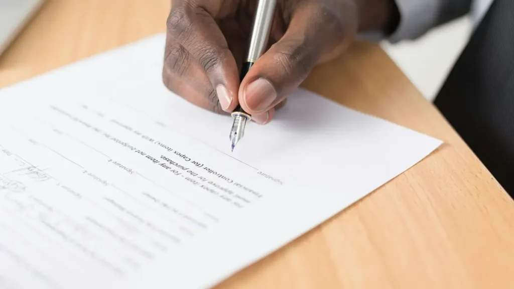 Main qui écrit avec un stylo sur une feuille de papier