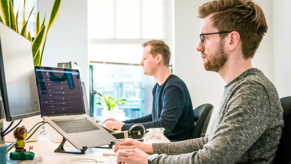 Deux collègues qui travaillent sur ordinateur dans un bureau lumineux