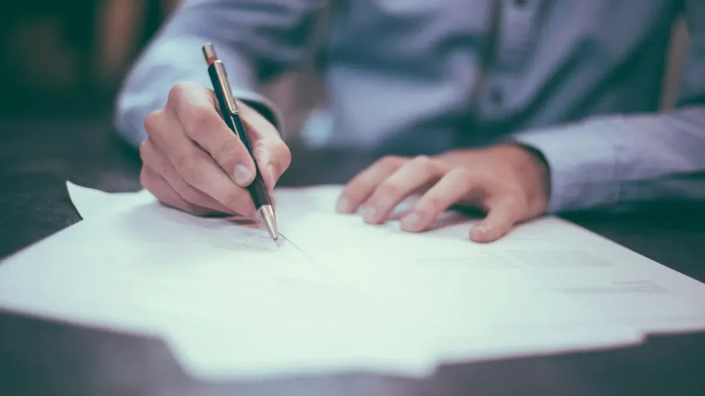 Main qui écrit sur une feuille avec un stylo
