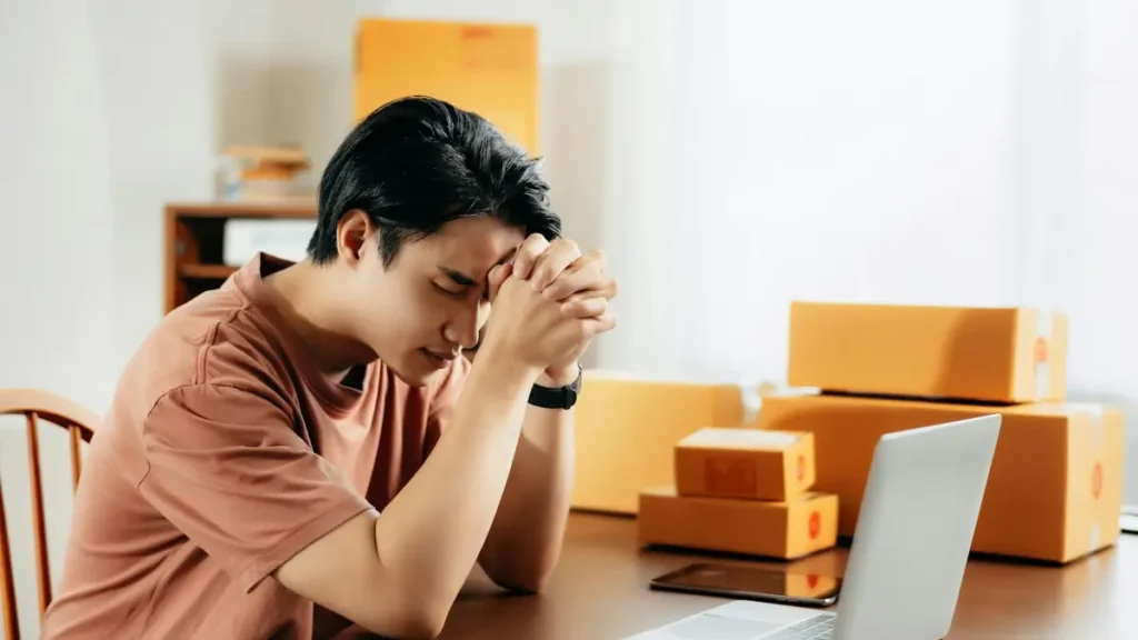 Homme préoccupé devant son ordinateur entouré de cartons