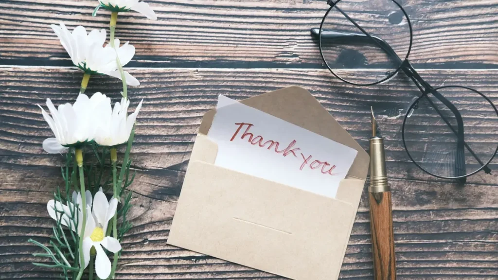 Carte de remerciement dans une enveloppe kraft, avec des fleurs et des lunettes