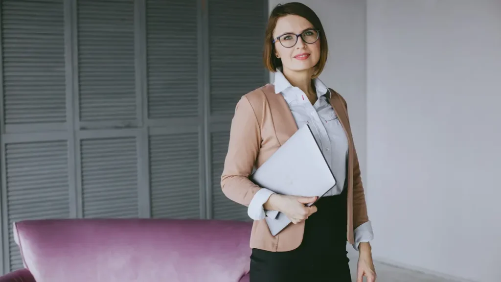Femme souriante tenant un ordinateur portable dans un bureau