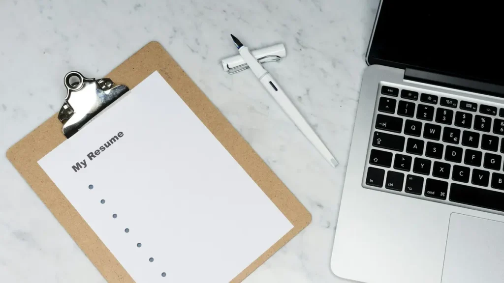 CV sur un porte-documents à côté d'un ordinateur portable et d'un stylo