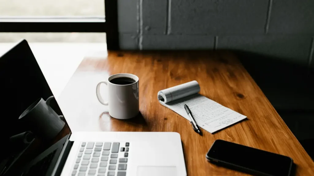 Ordinateur portable, tasse et bloc-notes sur un bureau en bois