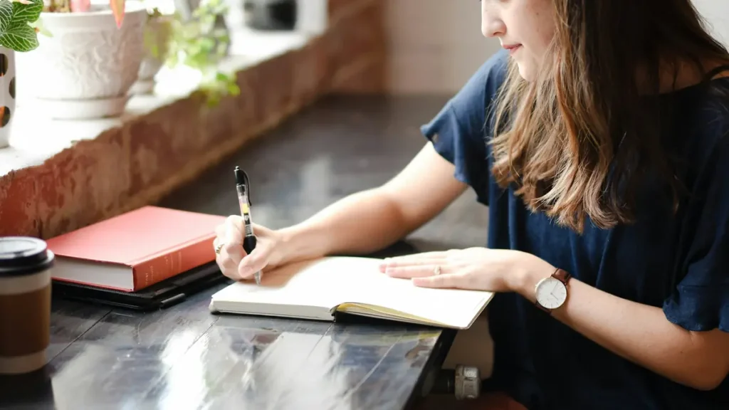 Lycéenne qui écrit dans un cahier près d'une fenêtre