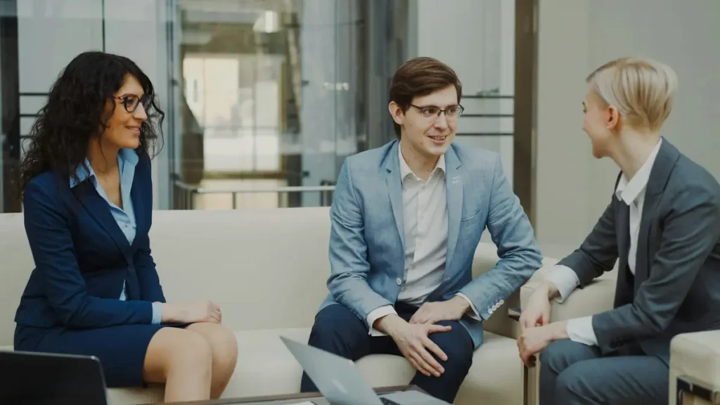 Trois personnes en discussion autour d'une table basse dans un bureau