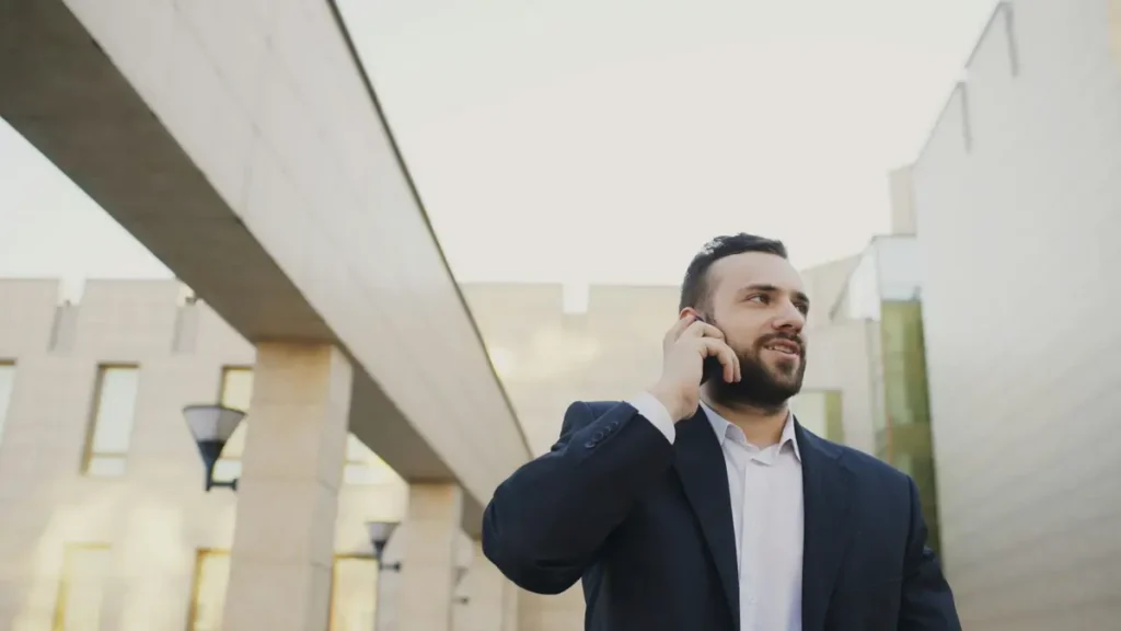 Homme en costume qui téléphone devant un bâtiment moderne