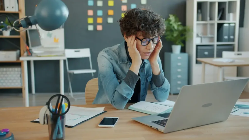 Jeune homme la tête entre les mains devant son ordinateur