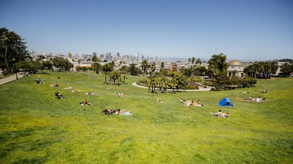 Pelouse d'un parc où des gens se reposent au soleil