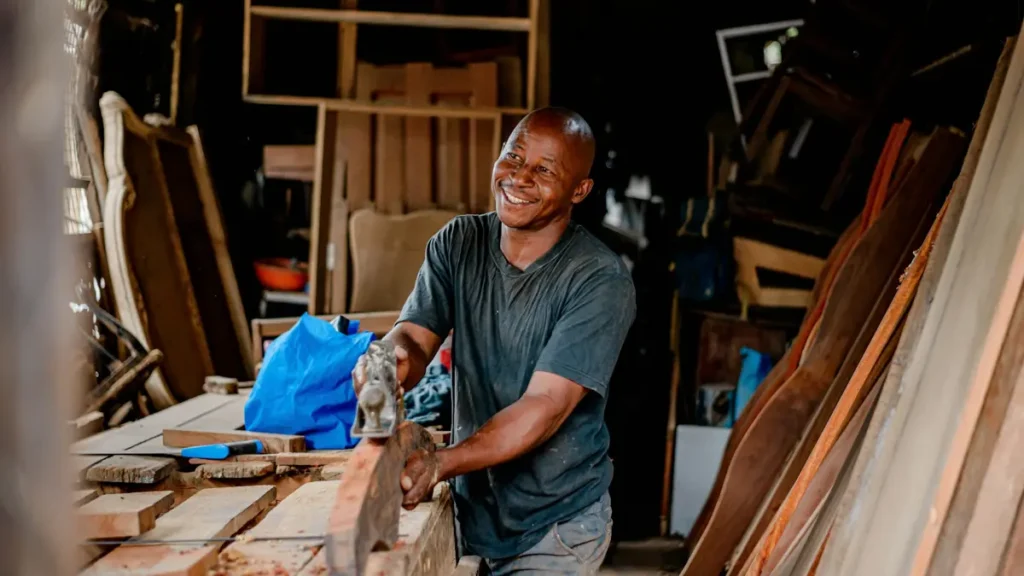 Apprenti menuisier souriant qui travaille une pièce de bois