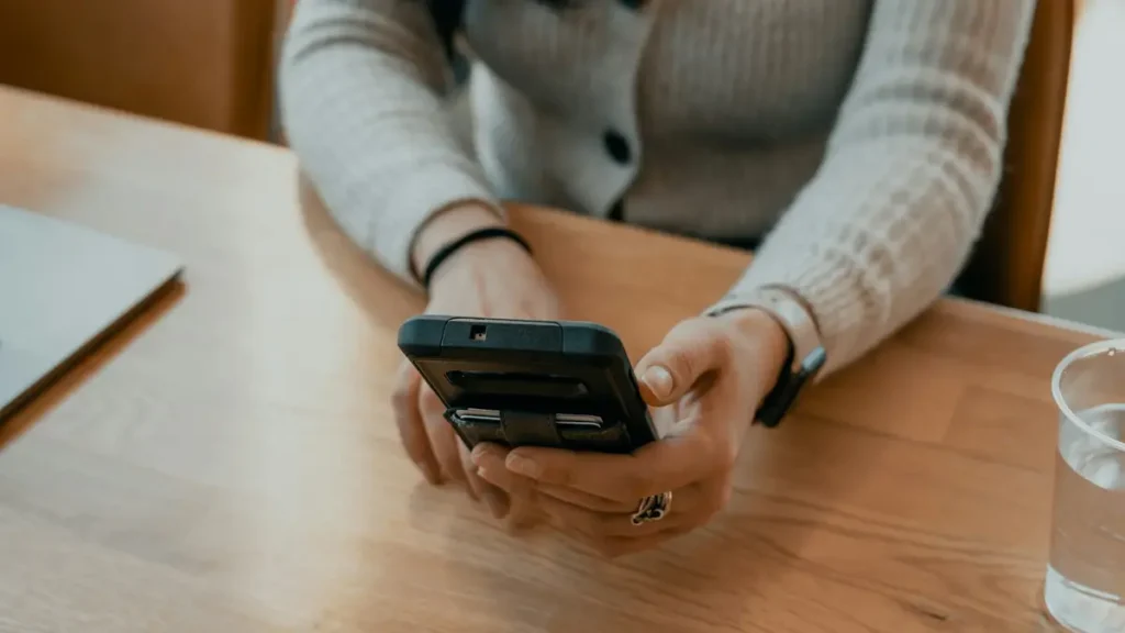 Mains tenant un téléphone sur une table en bois