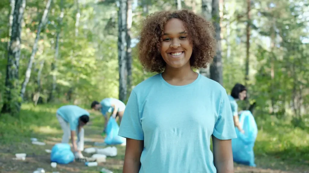 Jeune volontaire souriante lors d'une action de nettoyage en forêt