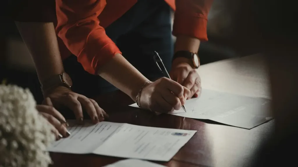 Personne qui signe un document posé sur une table