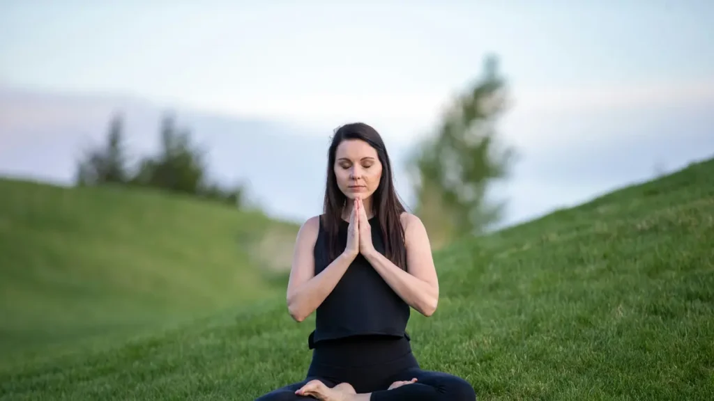 Femme qui médite assise dans l'herbe