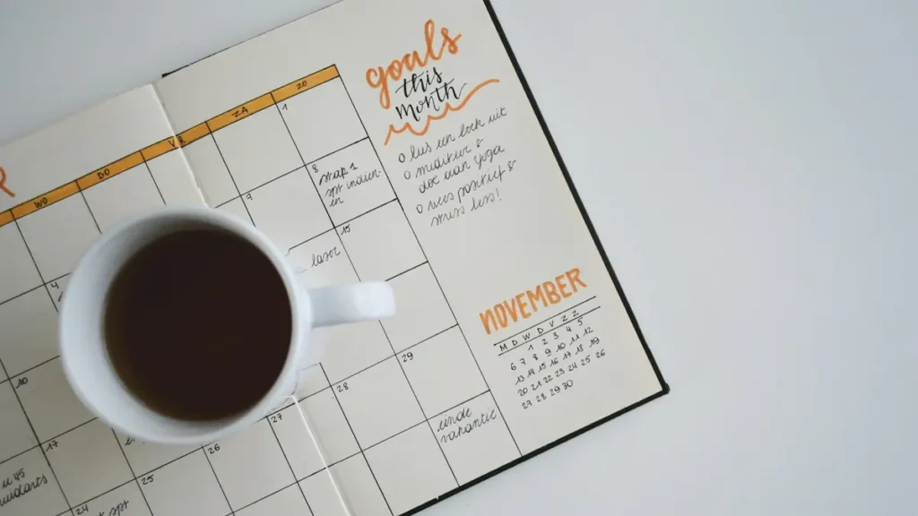 Agenda ouvert et tasse de café posés sur une table